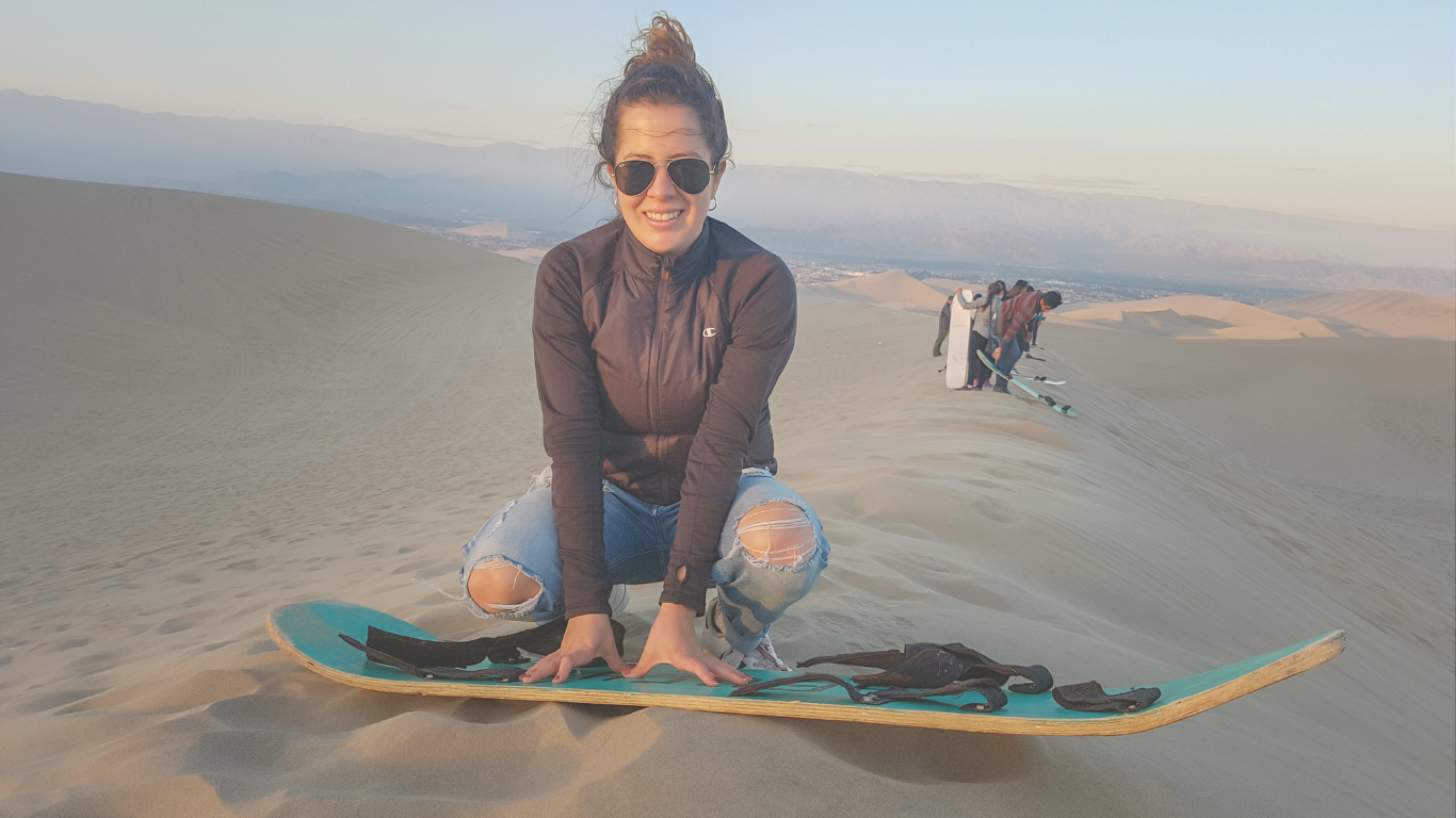 A young woman getting ready for sandboarding during a relaxed RV trip, embodying carefree casual camping fun.